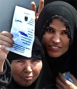 Two Iraq women voters wave ballot papers