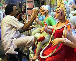 An artist adds finishing touches to a statue of Laxmi