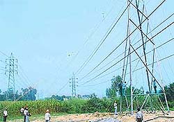 Punjab State Electricity Board employees install high tension power cables to raise their height for easing traffic on the Kharar bypass in Balongi near Kharar