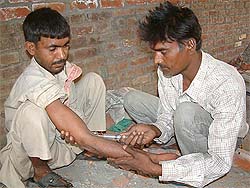 A migrant labourer being administered a drug injection by another addict in Amritsar�s Maqboolpura locality