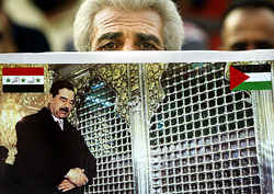 A Palestinian man holds a picture of Iraqi President