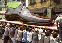 Filipino workers push a giant shoe