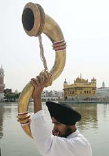 A Sikh priest blows a traditional horn