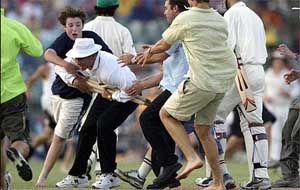 Cricket fans eager to get souvenir stumps swamp umpire A.R. Kerr, after running onto the field at the end of play in the traditional Ashes tour opening match