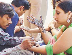 Mehndi artists busy apply henna on hands of customers.