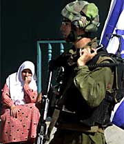 A Palestinian woman looks at an Israeli soldier