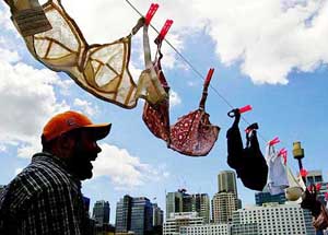 A man laughs as he walks past a line of over 500 hanging bras