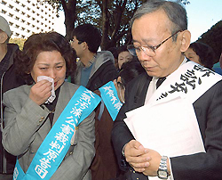 A plaintiff wipes her tears as she stands among other plaintiffs after a Japanese court