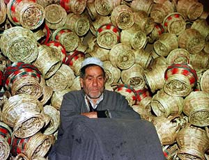 A Kashmiri sits in front of a heap of Kangris