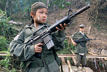 Samboo, a 12-year-old soldier in the Karen rebel army fighting against Myanmar's military, poses with his rifle