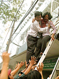 A survivor of a fire at the International Trade Center is helped down a ladder in Ho Chi Minh city on Tuesday.