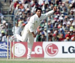 Sachin Tendulkar of India bowls to West Indies Chris Gayle