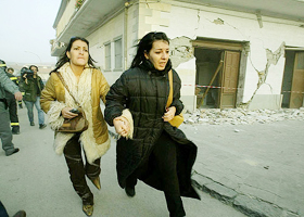 Two women run for cover as another strong tremor measuring 5.3 on the Richter scale rocks San Giuliano di Puglia