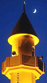 A crescent moon rises over a mosque's minaret in the Kuwait desert
