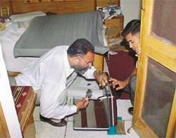 An expert collects fingerprints from burgled house