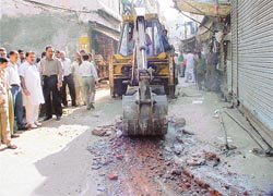 A bulldozer of the Municipal Corporation at work in Kucha Number 5, Field Ganj, Ludhiana, in the presence of the area councillor and shopkeepers