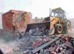 A bulldozer demolishes an illegal construction in the New Puneet Nagar area in Ludhiana