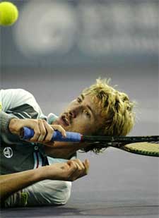 Juan Carlos Ferrero of Spain returns a shot as he lies on the floor in the final of the Tennis Masters Cup against World No 1