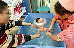 A Chinese father and a nursing assistant help the man's newborn son float