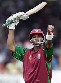 Marlon Samuels of the West Indies raises his bat after completing a century during the seventh and final one-day