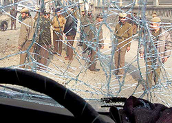 Policemen stand near the broken windscreen