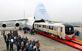 Two underground train carriages are unloaded from a cargo transport plane