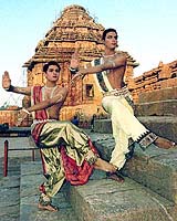 Two male dancers practice in front of a temple