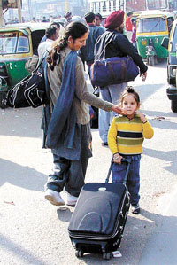 A child helps his mother drag their luggage as she looks around for conveyance to ferry