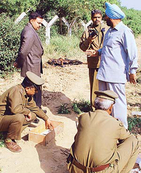 Police officials trace the footprints of persons who killed a youth 