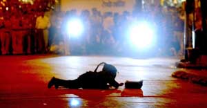 A bomb squad member dressed in protective gear crawls towards a bag suspected to contain explosives, in Mumbai