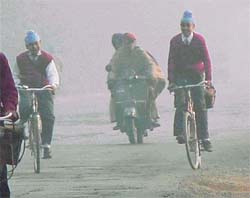 Schoolchildren cycle in fog while going to school