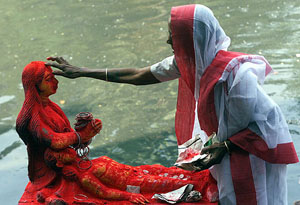 An elderly woman applies vermilion on the forehead