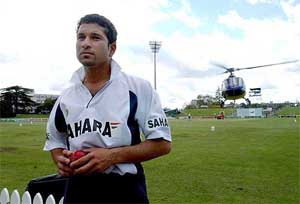 India's Sachin Tendulker looks on as a helicopter does some low flying