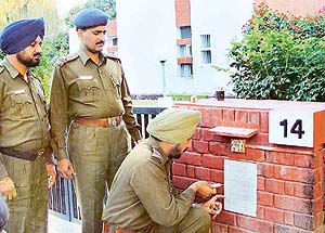 An ASI of Chandigarh Police pastes a notice outside the house of a senior Haryana bureaucrat, Mr N.K. Jain, in Sector 7, Chandigarh, on Saturday. 