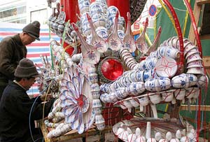 Two vendors install a dragon sculpture