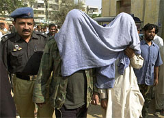 A policeman escorts members of the outlawed militant group