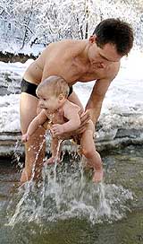 A Kazakh man holds his four-month-old son after bathing him in a mountain river