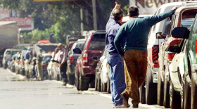 Venezuelan men wait in a huge line of cars waiting to purchase gasoline