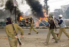 Policemen chase a mob after they set ablaze police and other vehicles in Patna on Tuesday 