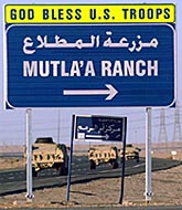 US Army Humvee utility vehicles pass a welcoming sign 