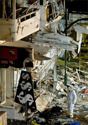 An Israeli policeman stands next to a dead body at a bombing site in Tel Aviv 