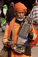 A sadhu plays a traditional musical instrument