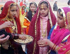 A girl distributes groundnuts and 'revris' on the eve of Lohri