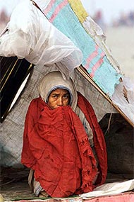 An elderly woman wraps herself in a shawl