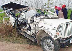 Villagers look at the jeep that was damaged in a head-on collision