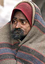 A slum dweller wraps himself in a blanket