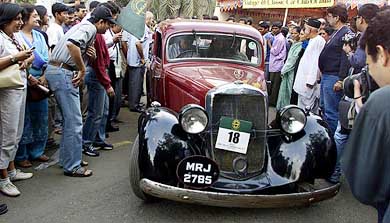 A contestant steers his 1937 Mercedes Benz through spectators during a Vintage car rally
