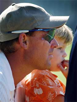 Shane Warne of Australia watches the game with his son Jackson
