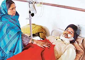 Mohammed Asgar, who was shot at by an unidentified person at Butrela village, being looked after by his wife