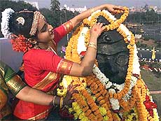 A woman places a garland on a statue of Subhas Chandra Bose on his birth anniversary